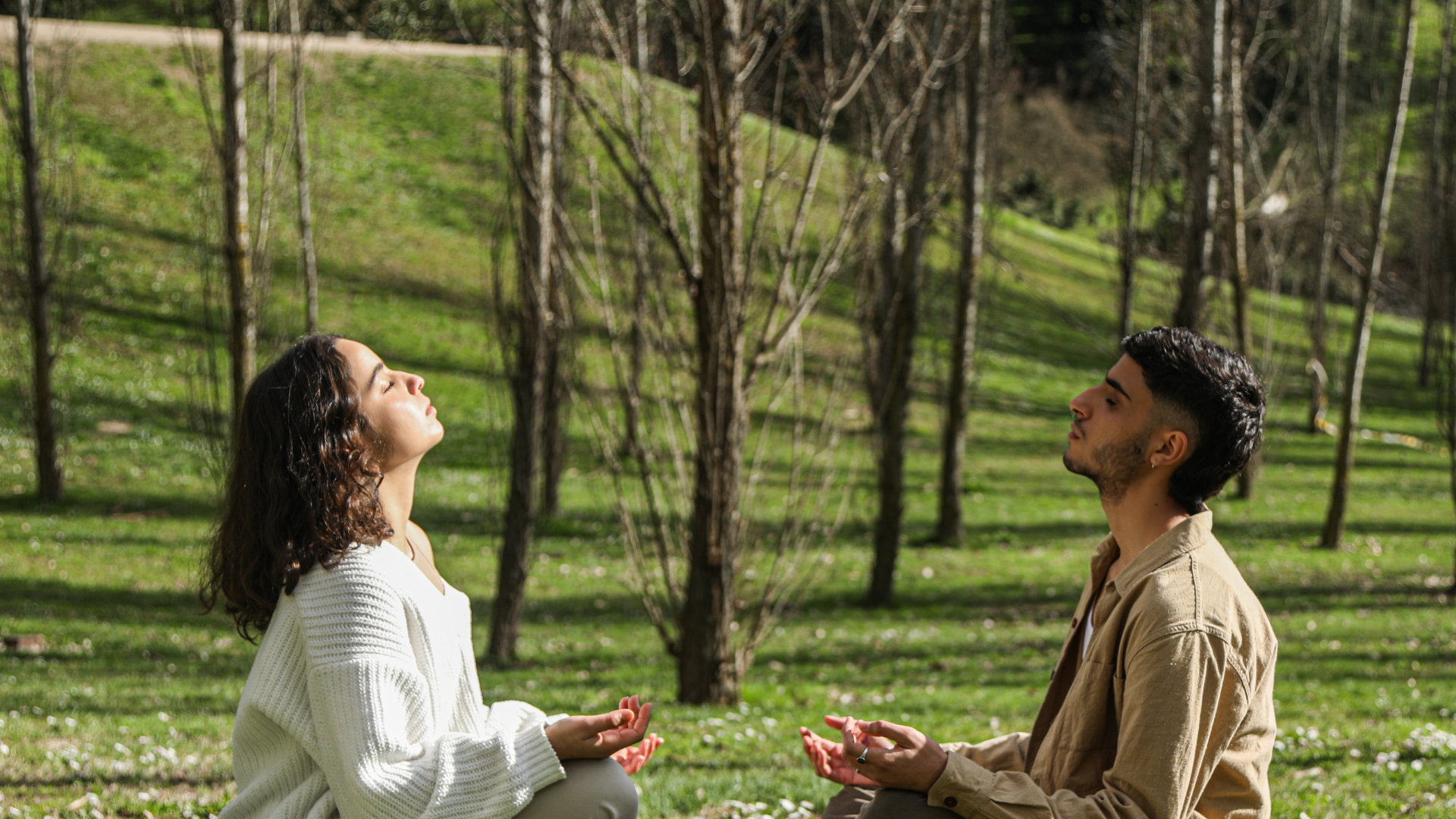 Dos personas meditando en un parque.